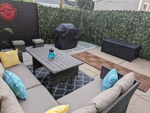 Private backyard with seating and propane grill with grilling utensils.