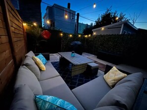 Private backyard with seating and propane grill with grilling utensils.