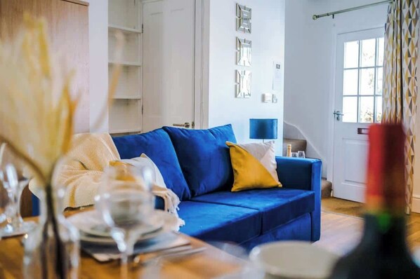 The living room is equipped with a sofa bed, 40-inch Smart TV with Netflix, and a dining area for up to 4 guests.