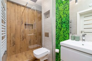 A stylish bathroom with wood-style tiles, a walk-in shower, and a bright green wall accent for a natural touch.
