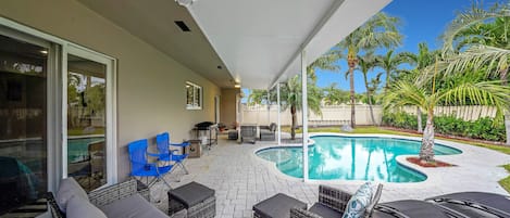 Enjoy the free-shaped pool outdoor! Relax in this outdoor couch, or in one of the two comfortable foldable blue chairs or get some sun on one of the lounge chairs! You also get a nice view of the yard with palms.