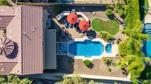 Private resort backyard with heated pool, jacuzzi, fire pit, BBQ, and loungers. 