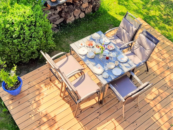 Gemütliche Holzterrasse mit Esstisch im großen Garten,