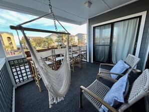 Main balcony with hammock swing, chairs, and bar height tables for 4.