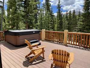 Large front deck with 6-person hot tub, Adirondack chairs, and dining table