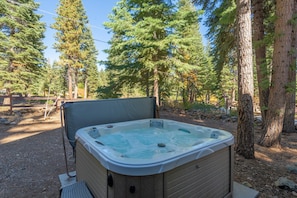 Hot tub is surrounded by tall trees and has amazing views.