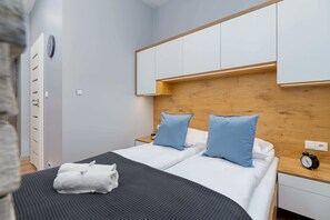 A cozy bedroom with a wooden accent wall, blue pillows, and neatly arranged linens for a relaxing atmosphere.
