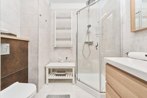 A sleek bathroom with a walk-in shower, wooden accents, and minimalist design.
