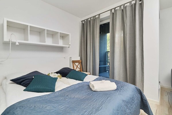 A cozy bedroom with a double bed, blue bedding, and soft curtains for a relaxing ambiance.
