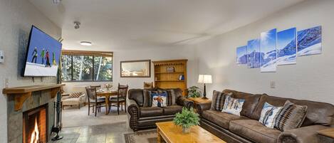 Living Room with plush leather furnishings, wood-burning fireplace, and 55" Smart TV