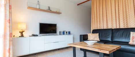 Wohnzimmer mit Sofa, Couchtisch und Sideboard mit TV
