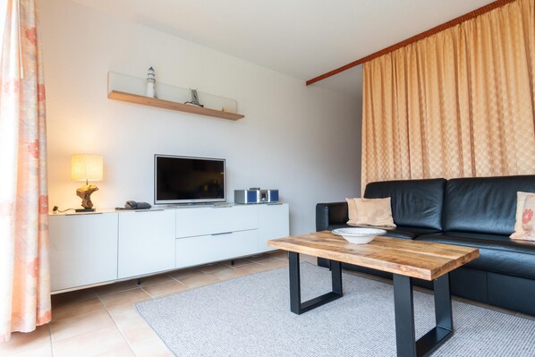 Wohnzimmer mit Sofa, Couchtisch und Sideboard mit TV