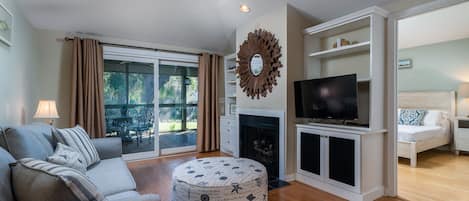 The great room has vaulted ceilings, sliding doors leading out to the screen porch, ceiling fan and Smart TV for streaming