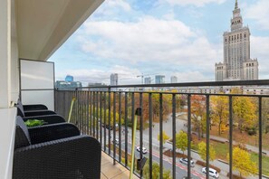 A private balcony with comfortable seating and a stunning view of the city skyline, including the Palace of Culture and Science.
