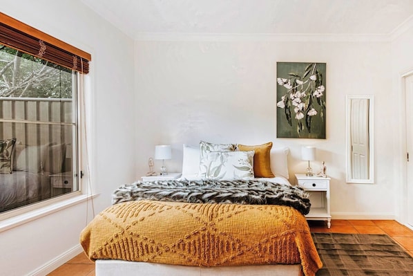 The first bedroom is bright and spacious with botanical styling and built-in wardrobes.
