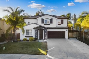 Welcome to our beautiful home! A spacious, modern retreat with lush palm trees, a well-manicured lawn, and a welcoming entrance.