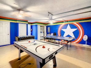 Avengers theme game room filled with TVs, foosball, ping pong, and air hockey