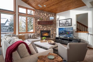 The living room hosts a large Smart TV, gas fire, and ample plush seating options