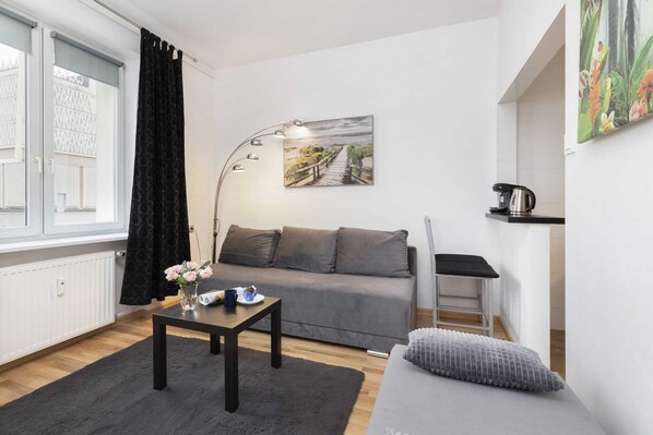 A bright living room with a gray sofa, a coffee table, and large windows allowing natural light to fill the space.

