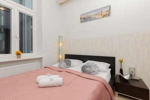 A bright bedroom featuring a comfortable bed with soft pink bedding and elegant decor.
