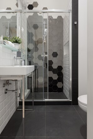 A sleek bathroom with a walk-in shower, dark tiles, and minimalist decor.
