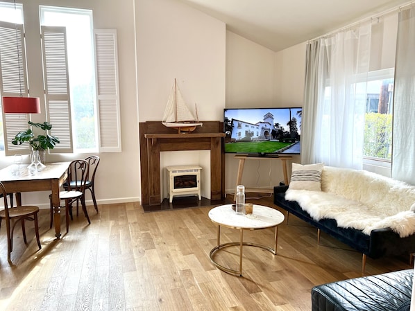 Voluminous living room with large HD TV, remote fireplace insert & natural light