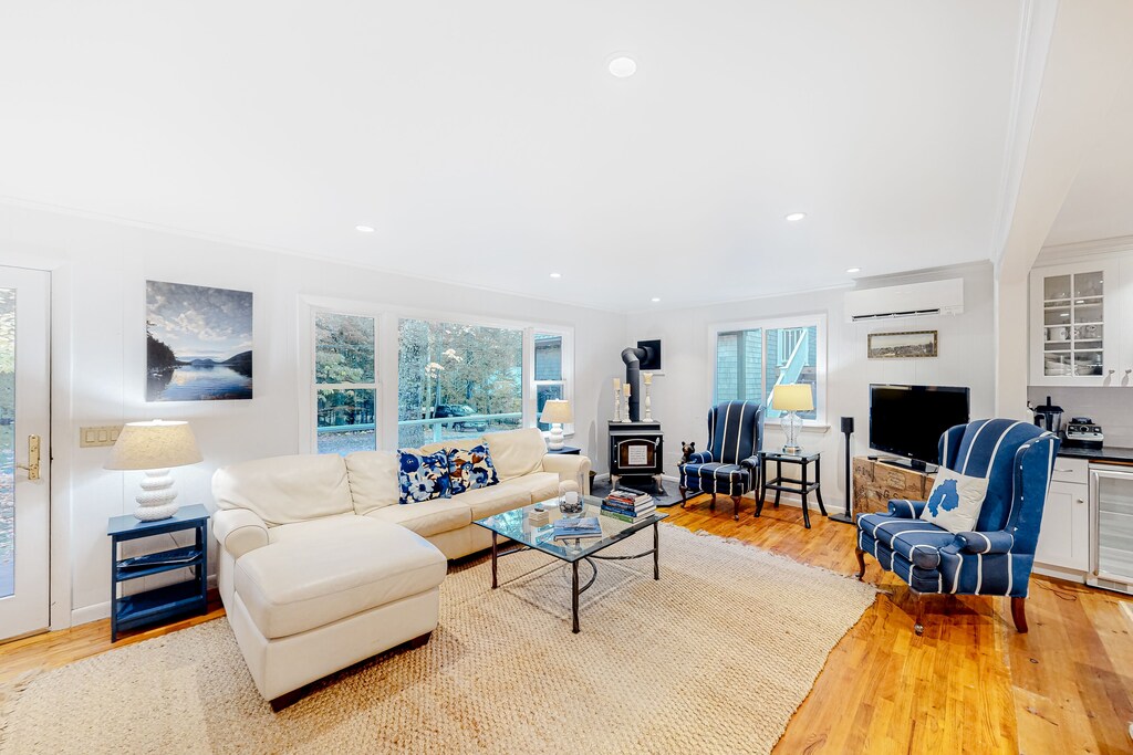 A spacious living space at a Mount Desert Island vacation rental has a large couch, two armchairs, and a glass table