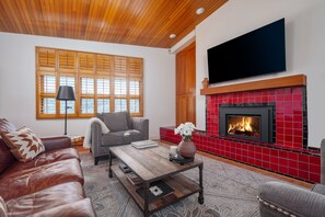 Sunny living room with vaulted cedarwood ceilings, 65" TV over the gas fireplace