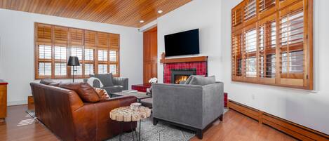 Sunny living room with vaulted cedarwood ceilings, 65" TV over the gas fireplace