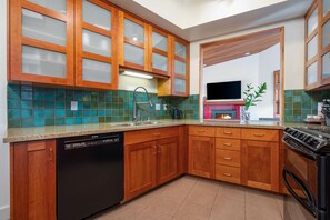 A fully stockes kitchen with stone countertops.