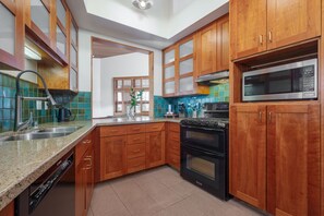 A fully stockes kitchen with stone countertops.