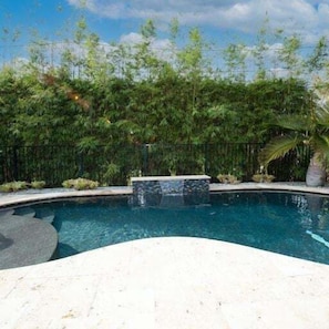 Heated teak pebble pool with waterfall feature