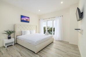 This bedroom features comfy king size bed. It also comes with a television and a large window that allows natural light to get in.