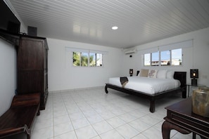 A bright and spacious bedroom with king size bed, a TV, a closet, and an air-conditioning unit for comfortable sleep.