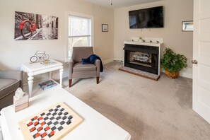 Living room with pull out sofa bed, games and fireplace.