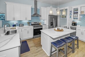 Well appointed kitchen, with quartz countertops, stainless steel appliances, and bar area complete with ice maker