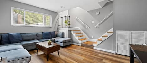 Living room; Unit entry way stairs on the left, and stairs leading upstairs on the right.