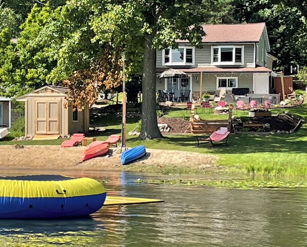 View of house from the lake. In picture is water trampoline & lily pad float.