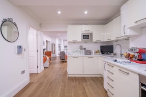 View from the dining table where you can see our fully equipped kitchen, living area and a door going to the bedroom.