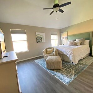 Modern and spacious room with a cozy couch, TV, and luxurious bedding