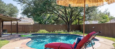 Large fenced backyard with pool, and covered patio.