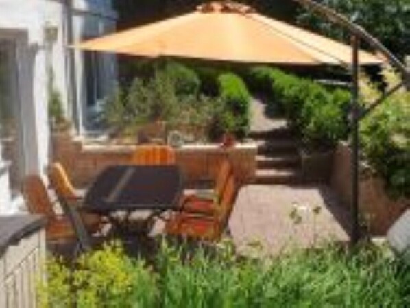 sonnige Terrasse mit Gartenmöbeln und Grill