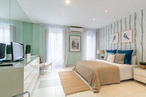 View of the bedroom, with double bed, two windows, a  chest of drawers and a  television.