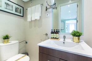 Bathroom with washbasin, toilet, mirror, shower and amenities