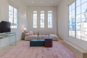 General view of the living room, with large windows, television and designer sofa.