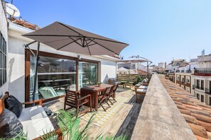 General view of the terrace with dining area, armchairs and umbrellas