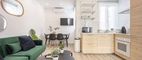 General view of the living room space with sofa, kitchen and dining room in the background