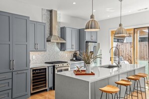 Cook like a chef in this high-finished kitchen with large island bar, wine fridge, gas stove, and stainless steel appliances.