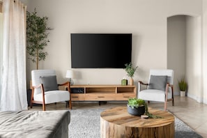 Living Room | Modern Design with Smart TV Relax in the stylish living room featuring cozy seating, a large smart TV, and plenty of natural light for a welcoming atmosphere.