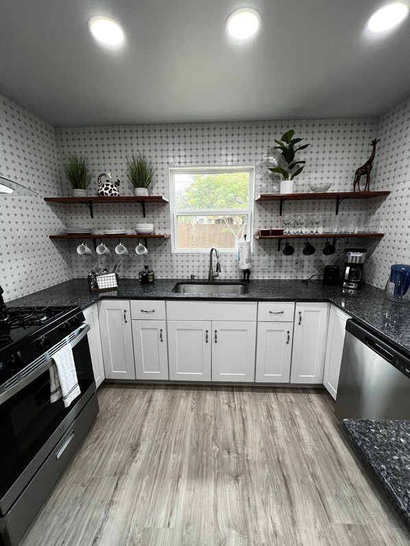 Kitchen with all the appliances and dish-ware. 